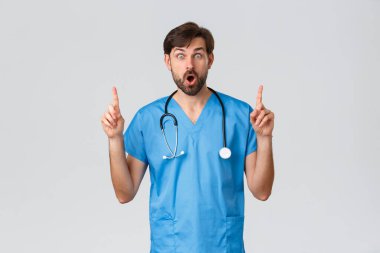 Sağlık çalışanları, koronavirüs karantina kampanyası ve salgın konsepti. Steteskopla mavi önlüklü, şaşırmış ve eğlenmiş doktor, işaret ediyor, nefes nefese, hemşire yol gösteriyor.