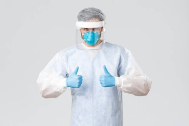 Covid-19, salgın hastalık, virüs salgınıyla mücadele eden sağlık çalışanları. Tıbbi koruyucu giysi, eldiven ve maske giyen kararlı bir doktor, koronavirüs hastalarıyla hastanede çalışıyor.