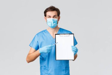 Covid-19, karantina, hastaneler ve sağlık çalışanları konsepti. Önlüklü, tıbbi maskeli ve eldivenli arkadaş canlısı doktor reçeteli ya da panoda bir şey yazıyor. Hastaya bir şey açıkla.