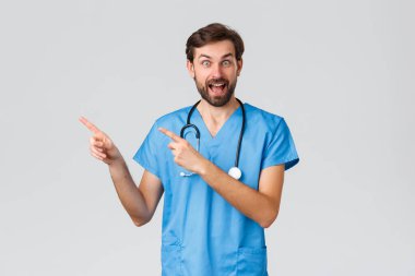 Sağlık çalışanları, salgın hastalık ve koronavirüs salgını konsepti. Heyecanlı sakallı doktor önlüklü, stetoskoplu, tanıtım, ilaç reklamı ya da hastane reklamları yapan, eğlen.