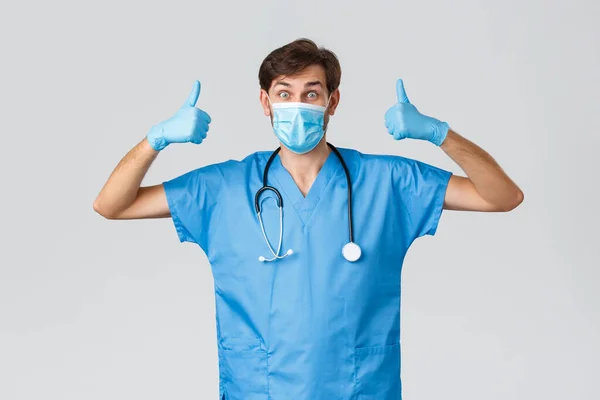 Sağlık çalışanları, koronavirüs karantina kampanyası ve salgın konsepti. Heyecanlı, doktor önlüğü, tıbbi maske ve eldiven takmış, steteskop boynunda, baş parmak yukarı, tamam, izin verin. — Stok fotoğraf