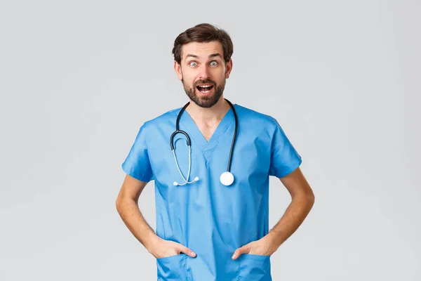 Covid-19, kwarantanna, szpitale i opieka zdrowotna. Zaskoczony i rozbawiony lekarz w fartuchu ze stetoskopem patrząc podekscytowany słysząc dobre wieści, porozmawiać, porozmawiać — Zdjęcie stockowe