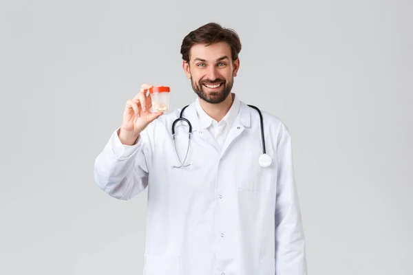 Krankenhaus, medizinisches Personal, covid-19 Behandlungskonzept. Schöner lächelnder Arzt in weißem Peeling mit Stethoskop, zeigt Tabletten, berät Patienten bei der Vorbeugung, zeigt Medikamente, Drogeriepromo — Stockfoto