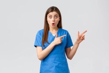 Sağlık çalışanları, virüsü, sigortayı ve ilaç konseptini engelleyin. Şaşırmış hemşire ya da doktor mavi önlüklü. İlginç haberleri dinleyin. Parmakla gösteriyorlar.