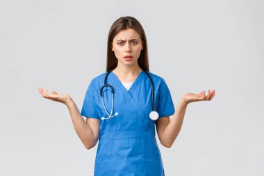 Sağlık çalışanları, virüsü, sigortayı ve ilaç konseptini engelleyin. Şaşkın ve şaşkın kadın hemşire, mavi önlüklü doktor, ellerini yana aç ve omuz silk, anlayamıyorum.