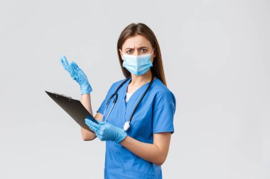Covid-19, virüsün önlenmesi, sağlık, sağlık çalışanları ve karantina konsepti. Mavi önlüklü ve tıbbi maskeli kadın hemşire ya da doktor, panoda saçma sapan şeyler okuyor.