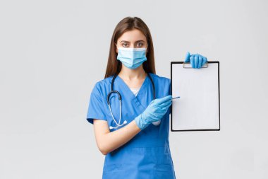 Covid-19, virüsün önlenmesi, sağlık, sağlık çalışanları ve karantina konsepti. Mavi önlüklü kadın hemşire ya da doktor, panodaki kağıda işaret ederek ilaç yazabilir.