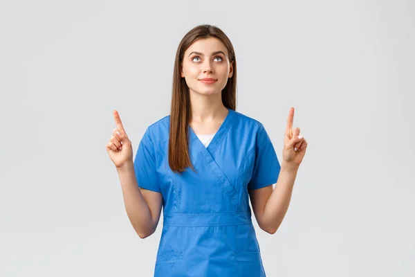 医療従事者,ウイルスを防止します, covid-19テストスクリーニング,医学の概念.若い才能のある医者、青い頭の女性看護師、指を指してサインやバナーを見て、灰色の背景 — ストック写真