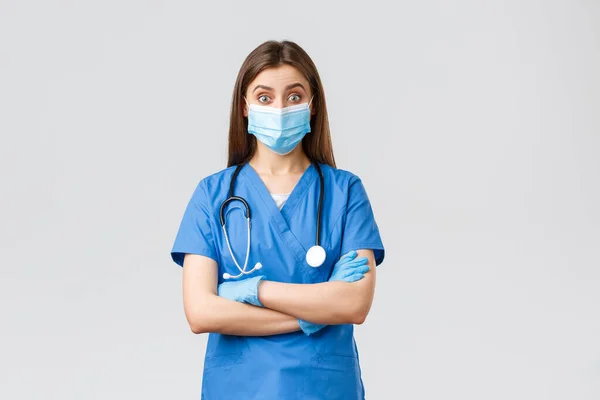 Covid-19, megelőzés vírus, egészségügyi dolgozók és karantén koncepció. Szórakoztató női orvos vagy nővér kék köpenyben sztetoszkóppal és egyéni védőfelszereléssel úgy néz ki, kíváncsi — Stock Fotó
