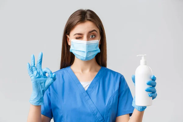 Covid-19, Prävention von Viren, Gesundheitspersonal und Quarantäne-Konzept. Selbstbewusst niedliche Krankenschwester oder Arzt in blauen Peelings, medizinische Maske und Handschuhe, genehmigen und empfehlen Seife oder Händedesinfektionsmittel — Stockfoto