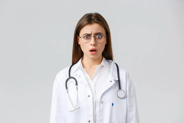 Sağlık çalışanları, ilaç, sigorta ve covid-19 salgını konsepti. Beyaz önlüklü, gözlüklü, doktor soluk soluğa ve endişeli kamerayla bakan şok olmuş kadın doktor. — Stok fotoğraf
