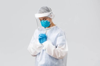 Covid-19, virüsün önlenmesi, sağlık, sağlık çalışanları ve karantina konsepti. Umut verici doktor ya da hemşire kişisel koruyucu giysi, yüz kalkanı ve tıbbi maske, hastaların koronavirüsü iyileştirmesi için dua ediyor.
