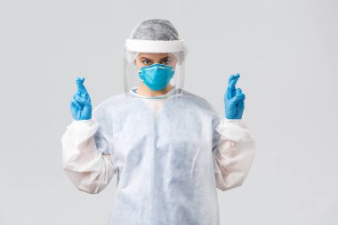 Covid-19, virüsü önleme, sağlık çalışanları konsepti. Doktor ya da hemşire kişisel koruyucu ekipman, solunum cihazı ve yüz kalkanı olan tıbbi giysi, umut dövüşü koronavirüs, şans dileyin.