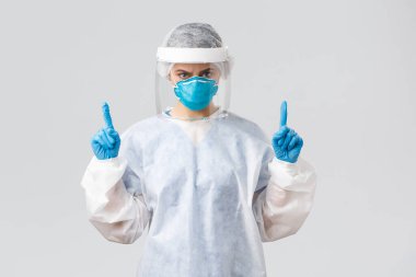 Covid-19, virüsün önlenmesi, sağlık, sağlık çalışanları ve karantina konsepti. Kızgın, kendine güvenen doktor ya da hemşire solunum cihazında, PPE tıbbi giysi ve eldivenler, kaşlarını çatma ve işaret etme