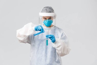 Covid-19, tıbbi araştırma, teşhis, sağlık çalışanları ve karantina konsepti. Ciddi bir doktor kişisel koruyucu ekipman, solunum cihazı, koronavirüs aşısı üretiyor, test tüpüne döküyor.