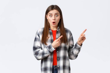 Yaşam tarzı, farklı duygular, boş zaman aktiviteleri konsepti. Vay canına, harika görünüyorsun. Şaşkın, genç, nutku tutulmuş, havalı yeni tanıtımlar yapan, parmaklarını sağ üst köşeyi gösteren ve kameraya bakan kız.