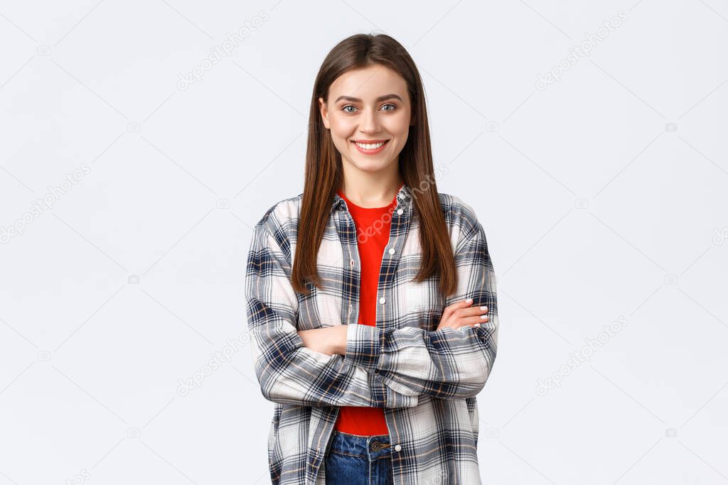 Lifestyle, different emotions, leisure activities concept. Cheerful young caucasian girl, female student in checked casual shirt, cross arms chest and demiling pleased, standing white background