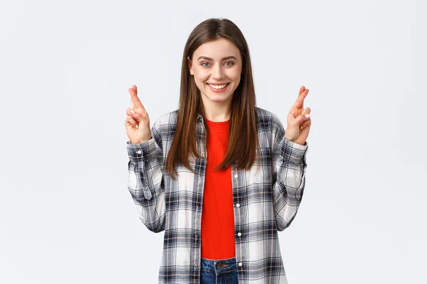 Estilo de vida, emociones diferentes, concepto de actividades de ocio. Esperanzado linda chica caucásica en camisa a cuadros, pidiendo deseo, dedos cruzados buena suerte y sonriente optimista, fondo blanco — Foto de Stock