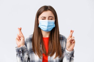 Coronavirus salgını, karantina, sosyal mesafeler ve duygu kavramı. Dilek tutan, gözlerini kapayan ve şans dileyen umut dolu, hayalperest genç kızın yakın çekimi.