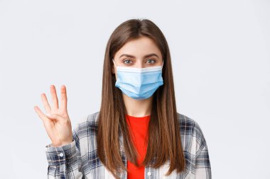 Coronavirus salgını, karantina, sosyal mesafeler ve duygu kavramı. Medikal maskeli neşeli çekici kadın dört numarayı gösteriyor. Düzen, beyaz arka plan.