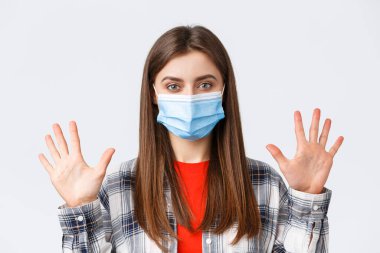 Coronavirus salgını, karantina, sosyal mesafeler ve duygu kavramı. Medikal maskeli çekici beyaz kadın on parmak, miktar ya da miktar gösteriyor, beyaz arka plan