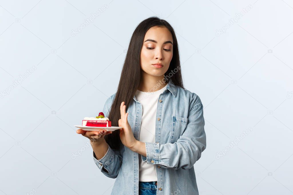 Social distancing lifestyle, covid-19 pandemic, celebrating holidays during coronavirus concept. Reluctant arrogant asian girl taking care of body, rejecting dessert, unwilling eat birthday cake