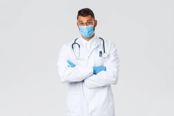 Covid-19, gezondheidswerkers, pandemie en het voorkomen van virus concept. Verrast Spaanse mannelijke arts in medisch masker en scrubs verhogen wenkbrauwen verbaasd, horen interessant geval in kliniek — Stockfoto