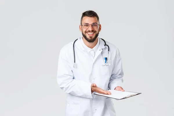 Travailleurs de santé, assurance médicale, laboratoire clinique et concept covid-19. Joyeux et soulagé beau médecin révèle de bons résultats de test de dépistage, patient souriant, pointez vers le presse-papiers — Photo