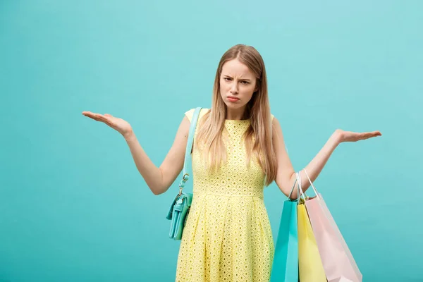 Compras y Venta Concepto: hermosa mujer joven infeliz en vestido elegante amarillo con bolsa de compras . — Foto de Stock