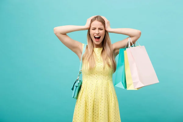 Compras y Venta Concepto: hermosa mujer joven infeliz en vestido elegante amarillo con bolsa de compras . — Foto de Stock