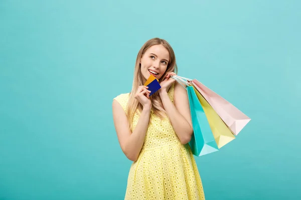 Nakupování a životní styl Koncept: Krásná mladá dívka s kreditní kartou a barevné nákupní tašky. Izolováno na modrém pozadí — Stock fotografie