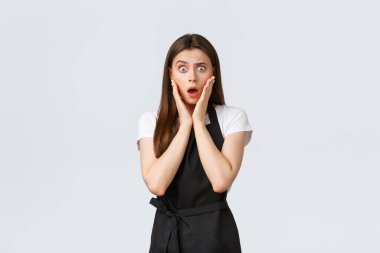Küçük işletmeler, çalışanlar ve kahve dükkanı konsepti. Siyah önlüklü, ağzı açık satış elemanı şok edici haberler duyuyor. Dedikodudan etkilenen bir kafe çalışanı, garson kendi gözlerine inanamıyor.