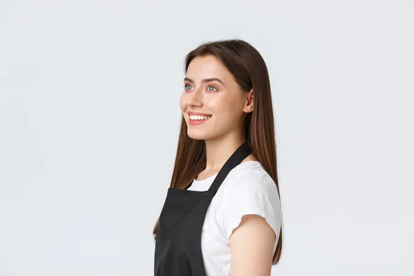 Employees, job employment, small business and coffee shop concept. Profile of barista,saleswoman in black apron react with excitement and surprise while looking left, white background — Stock Photo, Image
