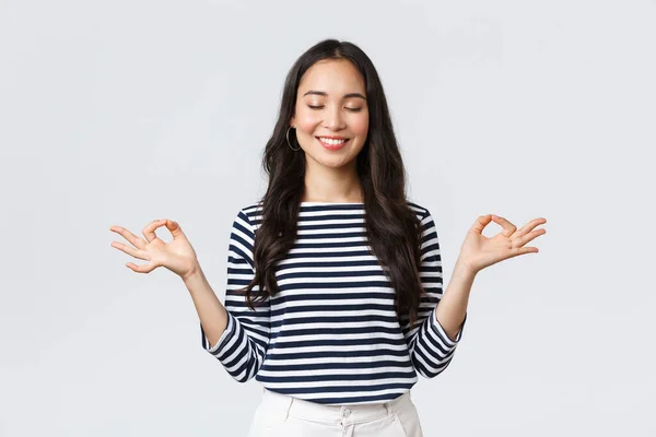 Livsstil, människors känslor och tillfälliga koncept. Lugn glad ung kvinna känner sig fridfull under meditation, blunda och ler som hålla händerna i zen nirvana gest, gör yoga motion — Stockfoto