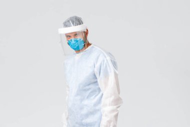 Covid-19 salgını, virüs salgını, sağlık çalışanları konsepti. Kişisel koruma ekipmanlarında ciddi kararlı doktor, kendine güvenen kamera, koronavirüs salgınıyla mücadele, hastaları tedavi