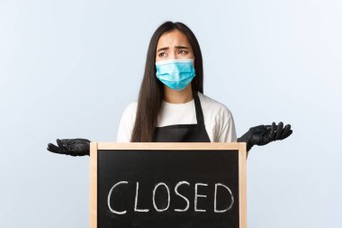 Küçük işletme, covid-19 salgını, virüs ve çalışanların konseptini engellemek. Tedirgin ve sıkıntılı kafe çalışanı ya da sahibi Coronavirus 'un kilitlenmesinden şikayetçi, çalışamıyor, kapalı tabelanın yanında omuz silkiyor.