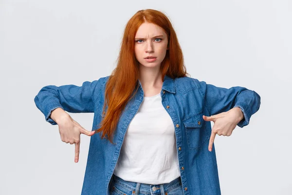Mad and disturbed, questioned redhead woman waiting answer on question, pointing fingers down, frowning angry and distressed, cat made mess while she was at work, scolding over white background — 스톡 사진