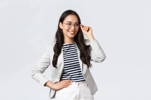 Negocios, finanzas y empleo, concepto de emprendedoras exitosas. Mujer de negocios segura en gafas y traje blanco listo para la reunión, sonriendo complacido, de pie determinado —  Fotos de Stock