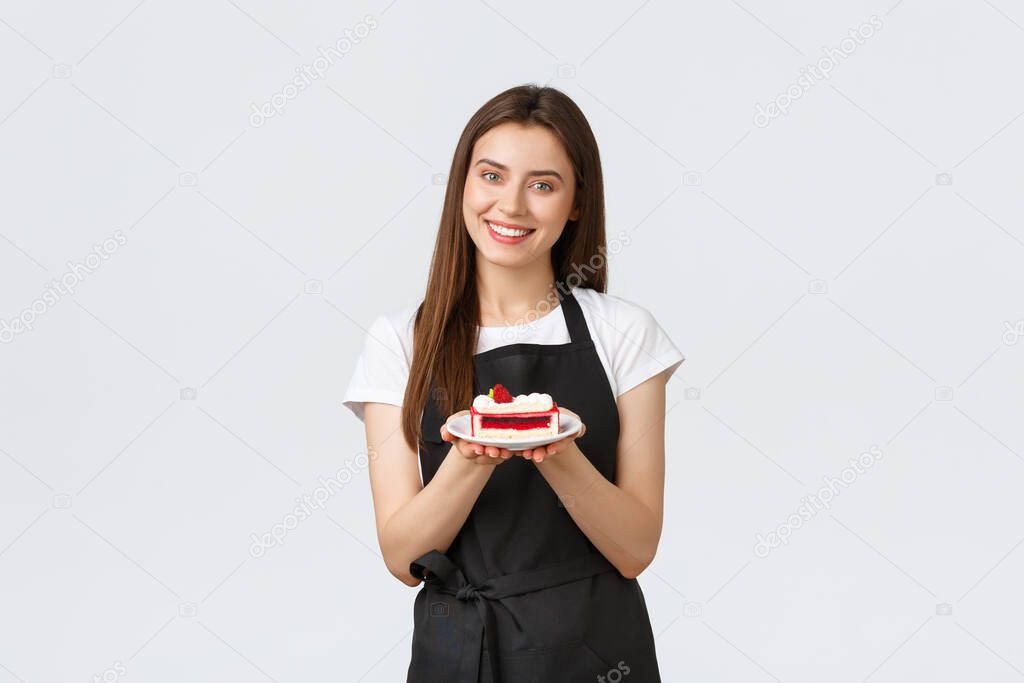 Grocery store employees, small business and coffee shops concept. Friendly smiling cafe worker serving dessert on plate. Cute barista in black apron give guest new delicious cake from menu