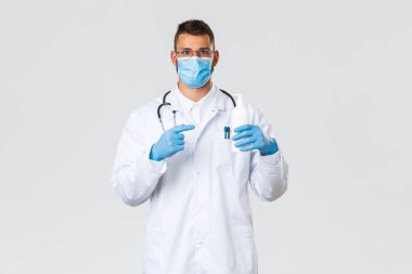 Covid-19, sağlık çalışanları, salgın hastalıklar ve virüs önleme konsepti. Tıbbi maske ve eldiven giyen İspanyol doktor, önlüklü doktor sabun tavsiye ediyor, el dezenfektanını işaret ediyor.