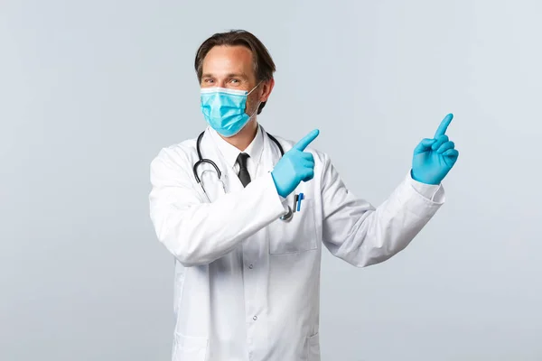 Covid-19, virüsü önleme, sağlık çalışanları ve aşı konsepti. Karizmatik memnun doktor tavsiye ver, reklamda sağ üst köşeyi gösteren tıbbi maske ve eldivenler tak — Stok fotoğraf