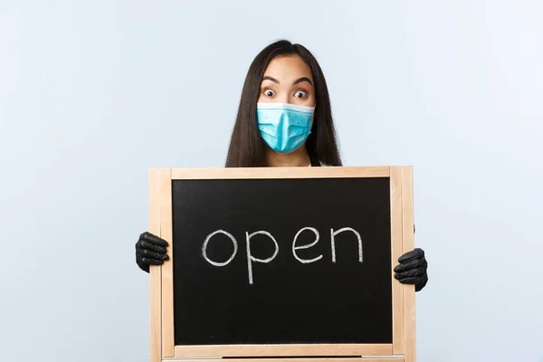 中小企業、 covid-19パンデミック、ウイルスや従業員の概念を防止します。興奮アジアの女性カフェの所有者は最終的に店をオープン発表し、医療マスクを着用し、サインを保持 — ストック写真