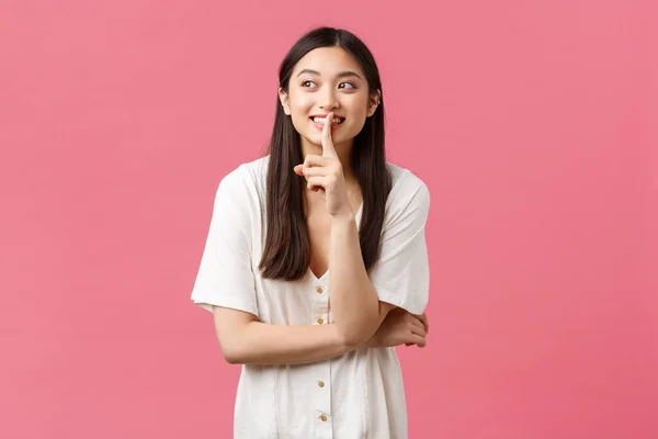 Belleza, emociones de la gente y concepto de ocio de verano. Soñador y lindo, hermosa chica asiática callando, pidiendo guardar silencio o no decirle a nadie su secreto, mirando hacia otro lado y sonriendo mientras chismorrea — Foto de Stock