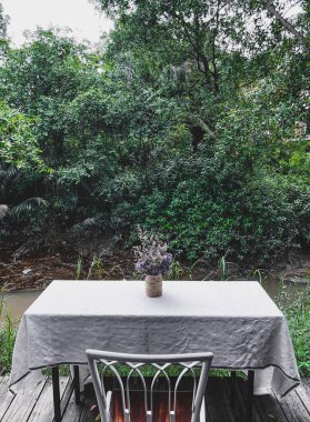 Kafe masaları ve sandalyeler dışarıda, tropikal arka planda..