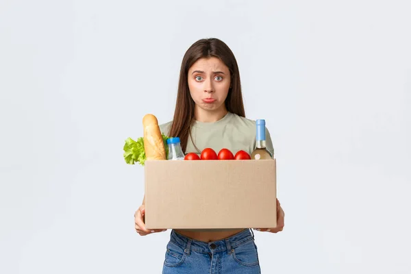 Online levering aan huis, internet bestellingen en boodschappen concept. Teleurgestelde vrouwelijke klant ontvangt verkeerde volgorde van boodschappen, kijken boos binnen doos en pruilen, staan witte achtergrond — Stockfoto