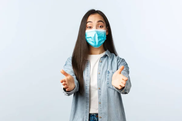 Social distanslivsstil, covid-19 pandemisk vardag och fritidskoncept. Le asiatisk kvinna i medicinsk mask sträcker händerna framåt för att ta eller hålla något bedårande — Stockfoto