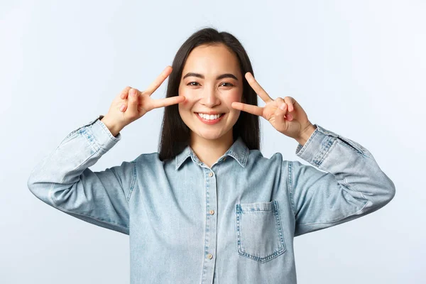 Estilo de vida, emoções das pessoas e conceito de beleza. Close-up de alegre sorridente asiático menina mostrando v-sign paz sobre os olhos, pé kawaii pose, sentindo-se despreocupado e otimista — Fotografia de Stock