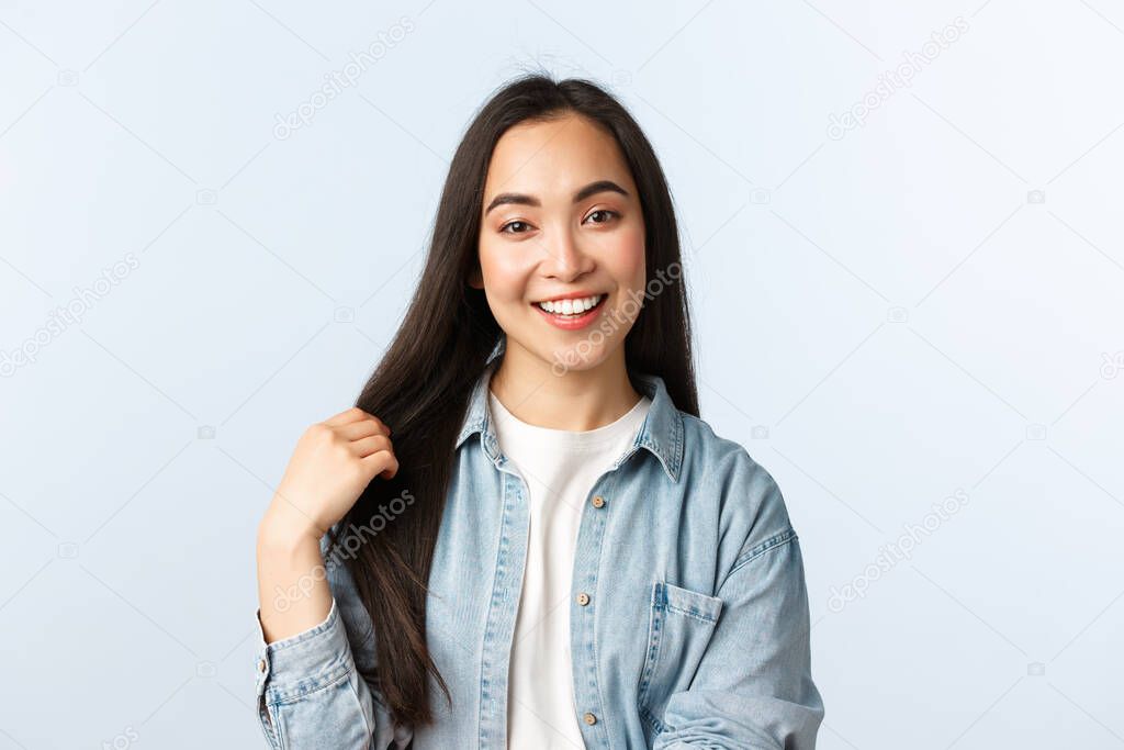 Lifestyle, people emotions and beauty concept. Carefree young asian woman talking and smiling, touching hair, recommend haircare products or beauty salon, white background