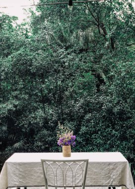 Kafe masaları ve sandalyeler dışarıda, tropikal arka planda..