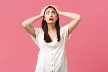 Güzellik, insan duyguları ve yaz tatili konsepti. Panik içindeki umutsuz ve hayal kırıklığına uğramış genç Asyalı kadın, gökyüzüne bak Tanrım yardım et, başınızı dik tutun, endişeli pembe arka plan